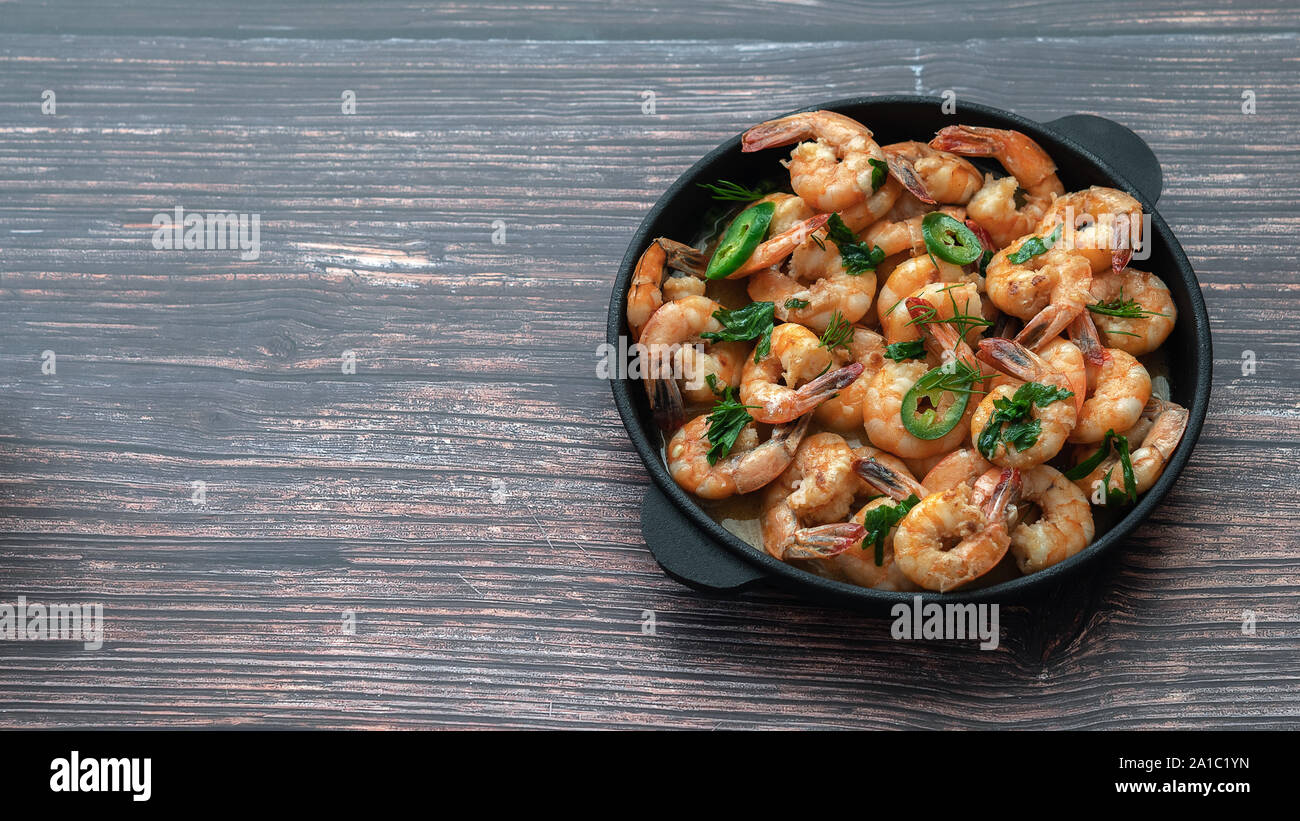 Fried shrimp close-up in creamy sauce in a cast iron pan on the left column free space Stock Photo