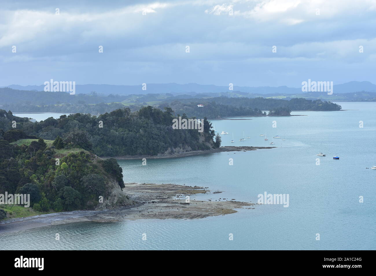Tiny bays and peninsulas with rocky reefs and platforms exposed at low tide and moored recreational vessels in Mahurangi Harbour near Auckland in New Stock Photo