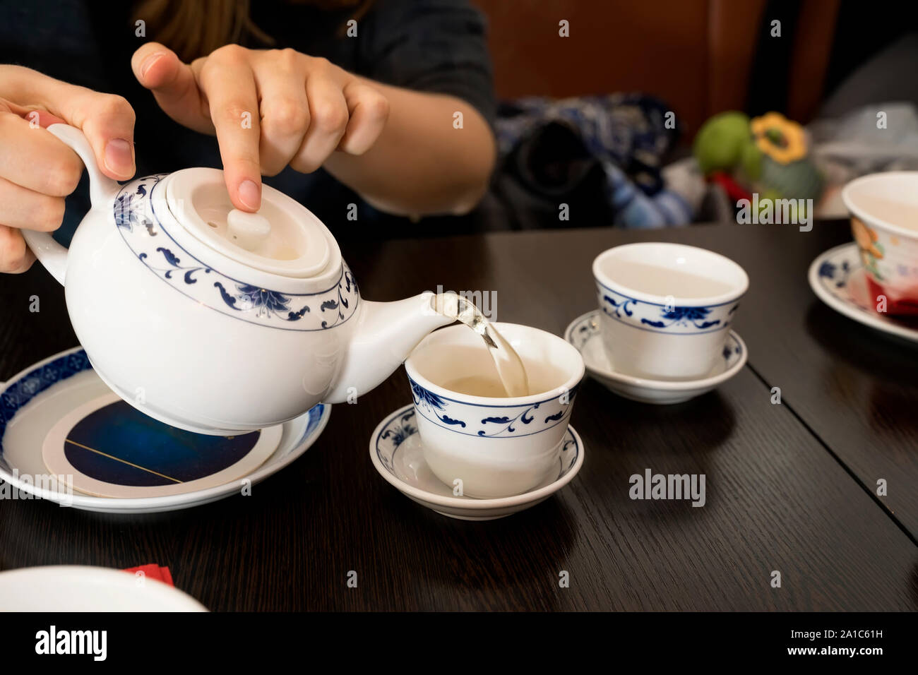 Teapot in the hands of a girl pouring green tea into beautiful chinese cups Stock Photo