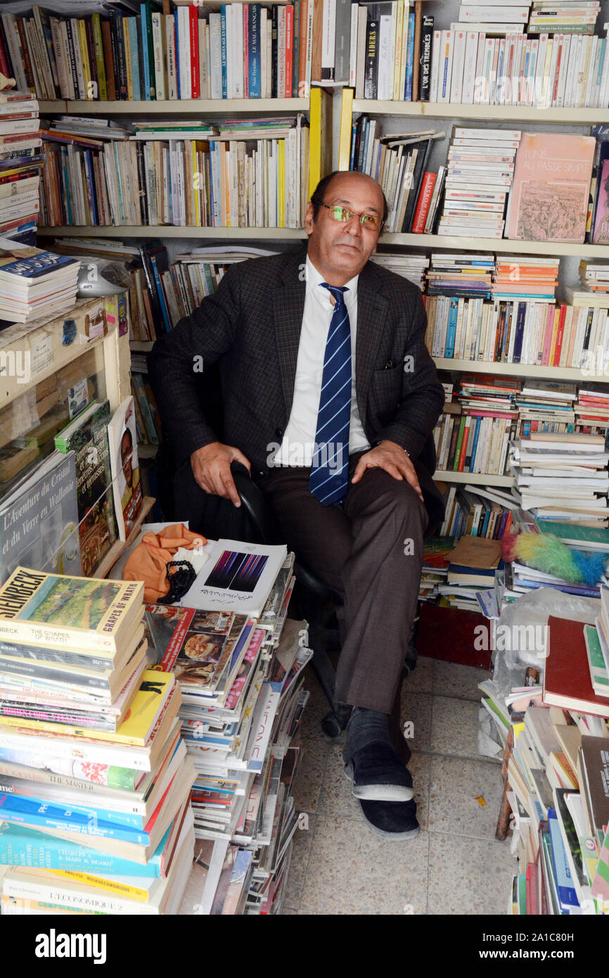 A Tunisian bookseller sitting in his bookshop in the market of the kasbah, in the medina of Tunis, Tunisia. Stock Photo