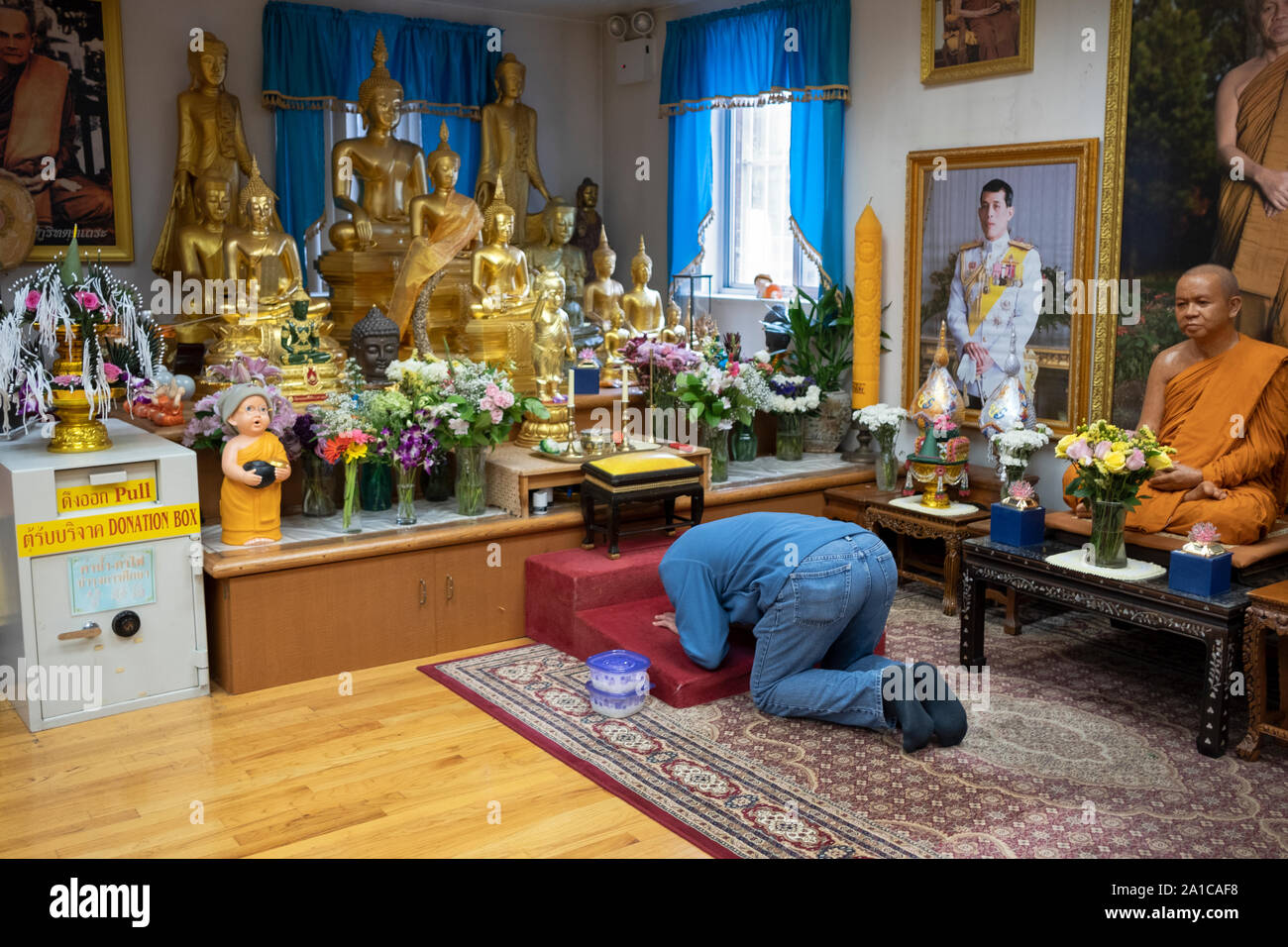 An anonymous devout Buddhist bows in prayer & meditation before statues