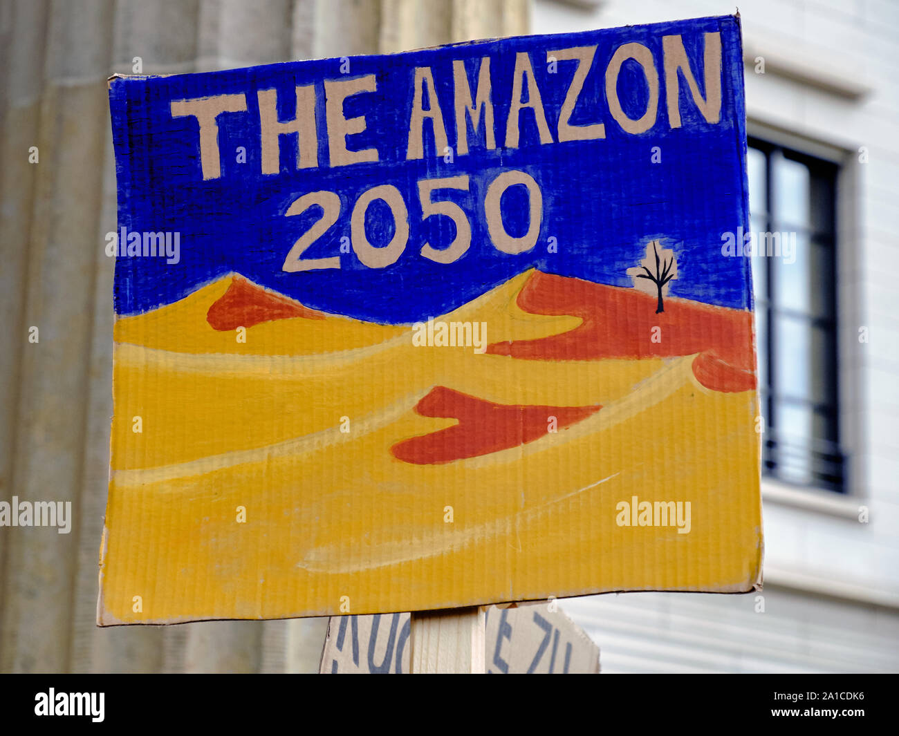 Placard 'The Amazon 2050' with desert landscape on a global climate strike by Brandenburg gate in Berlin Stock Photo