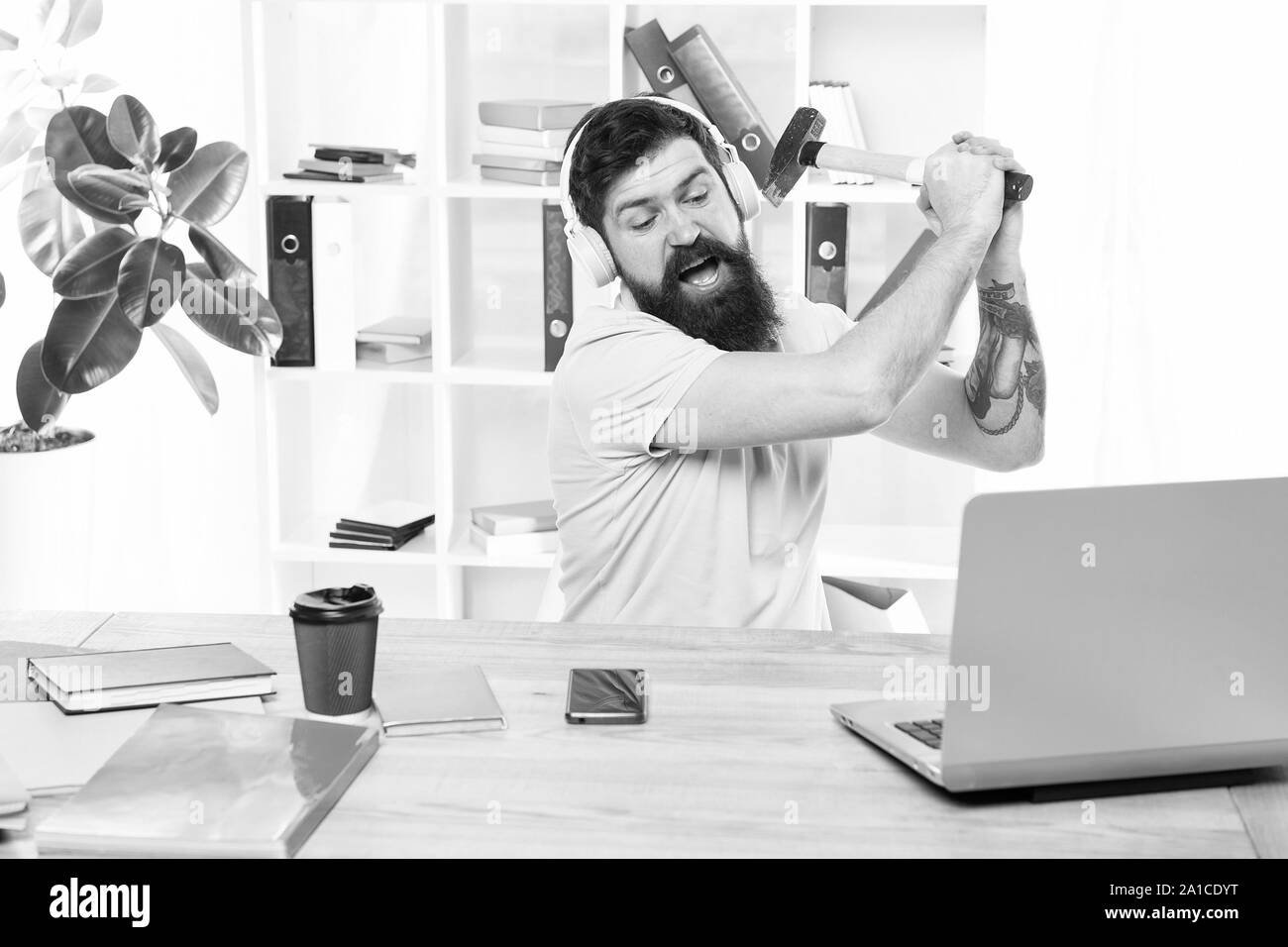 Slow internet connection. Outdated software. Computer lag. Reasons for computer lagging. How fix slow lagging system. Hate office routine. Man bearded guy headphones office swing hammer on computer. Stock Photo