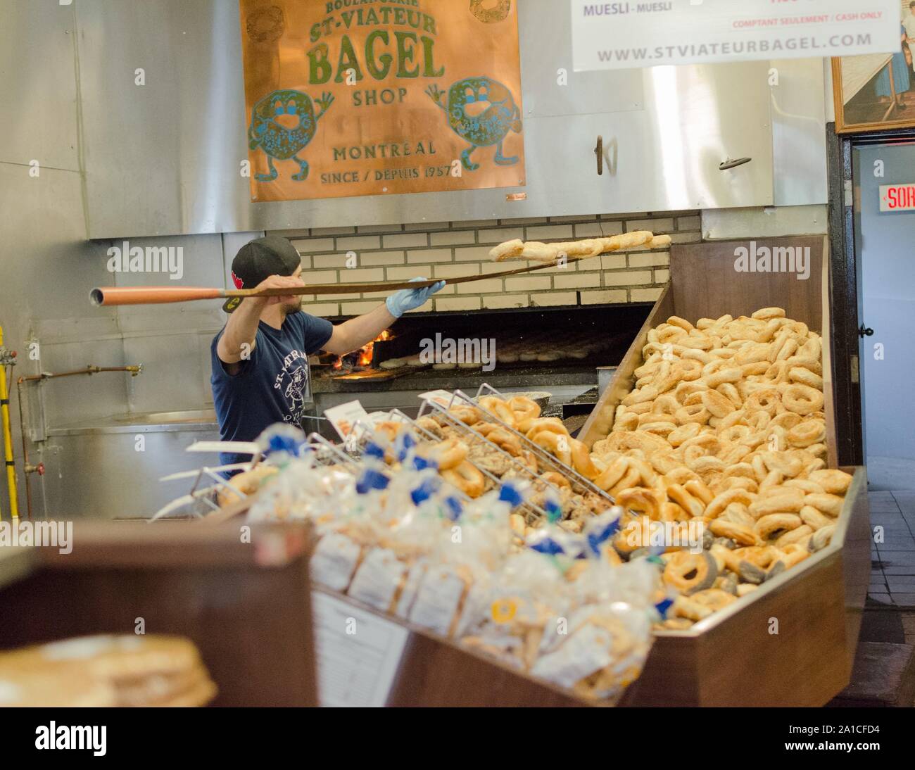 A worker removes fresh Bagels from the oven at St. Viateur Bagel in Montreal Canada. Stock Photo