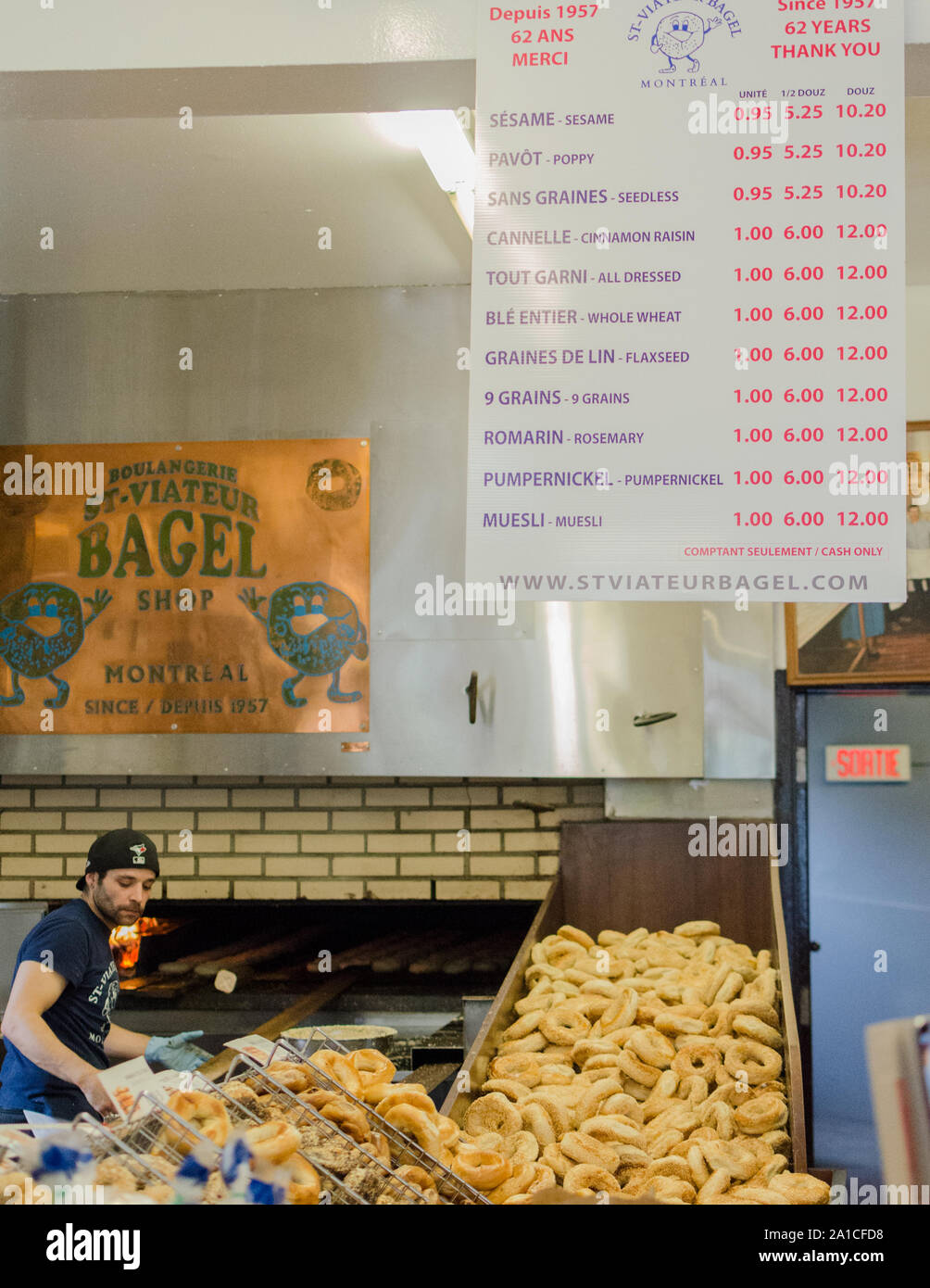 A worker removes fresh Bagels from the oven at St. Viateur Bagel in Montreal Canada. Stock Photo