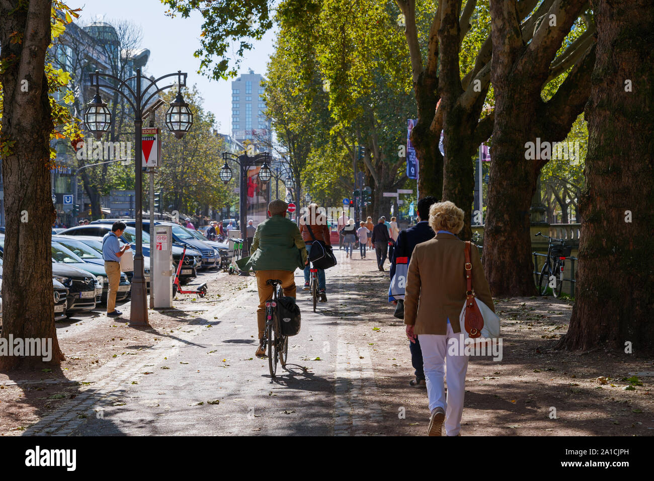 People walk and ride bicycle on beautiful shady sidewalk and bicycle