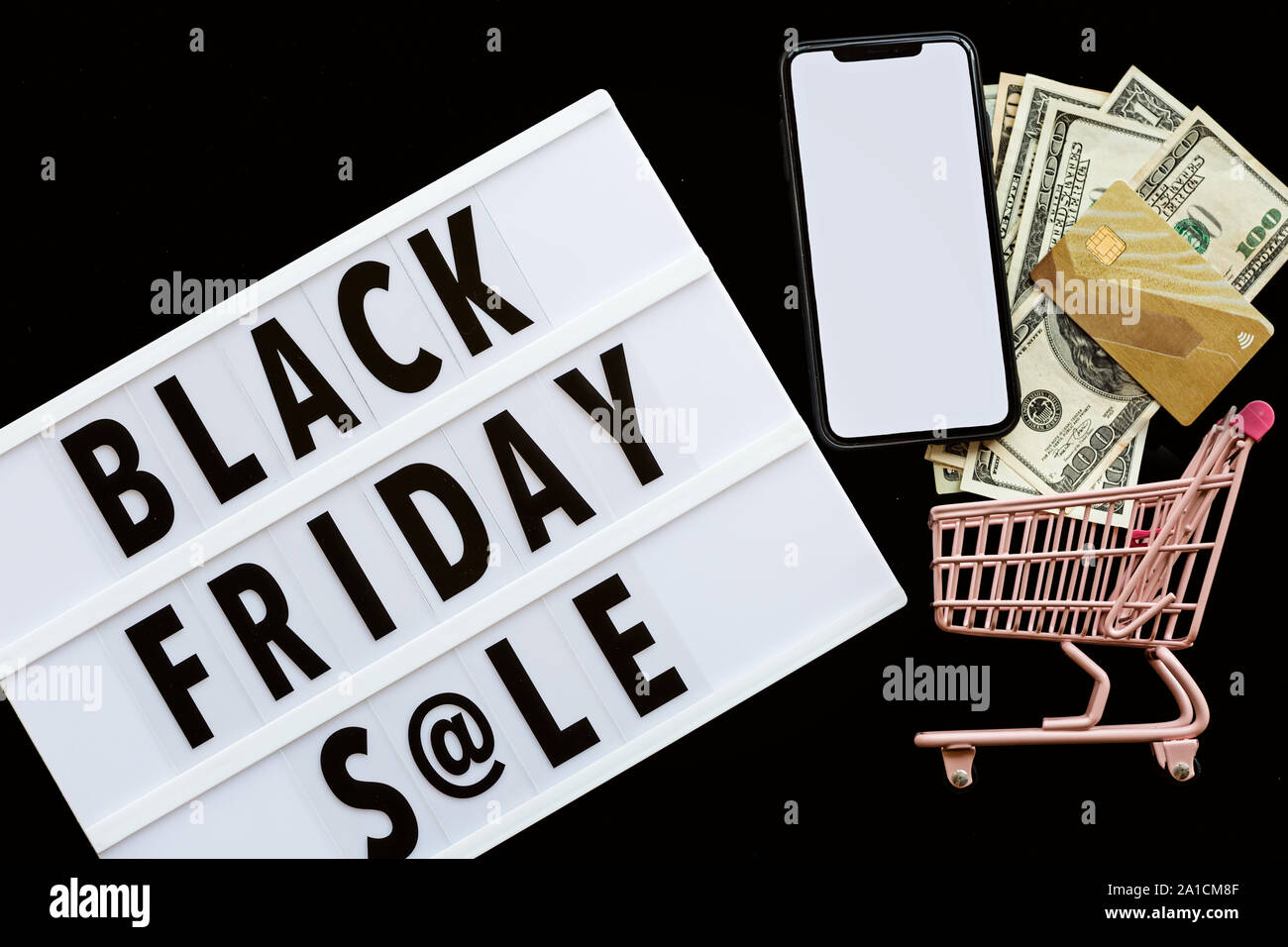 Creative promotion composition Black friday sale text on lightbox on black  background, next grocery trolley, mobile phone, credit card, cash money  Stock Photo - Alamy