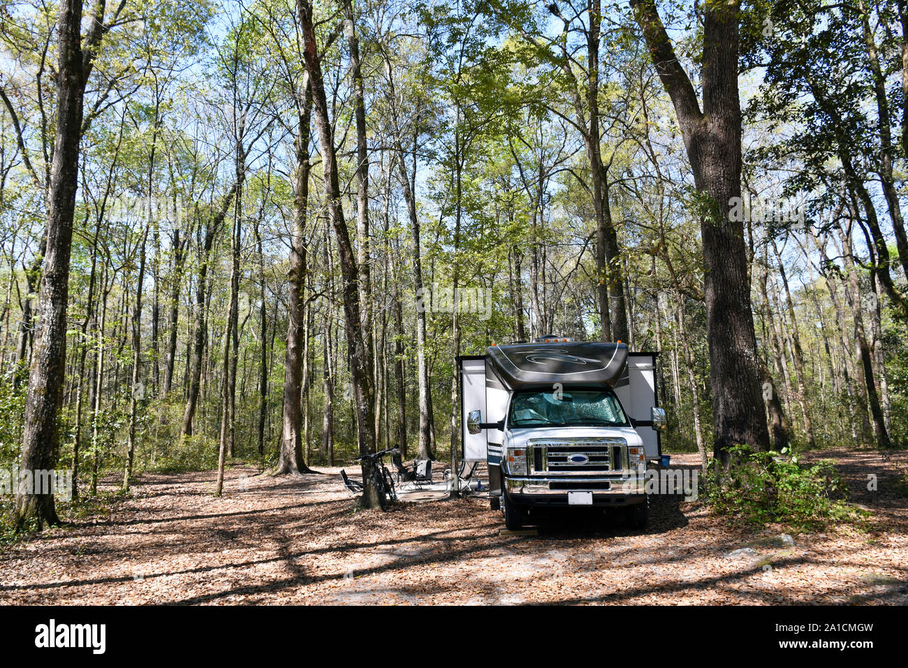 A large Class C RV caravan with slides is seen at the campground at Ichetucknee Springs State Park in Florida, a beautiful area off the beaten path. Stock Photo