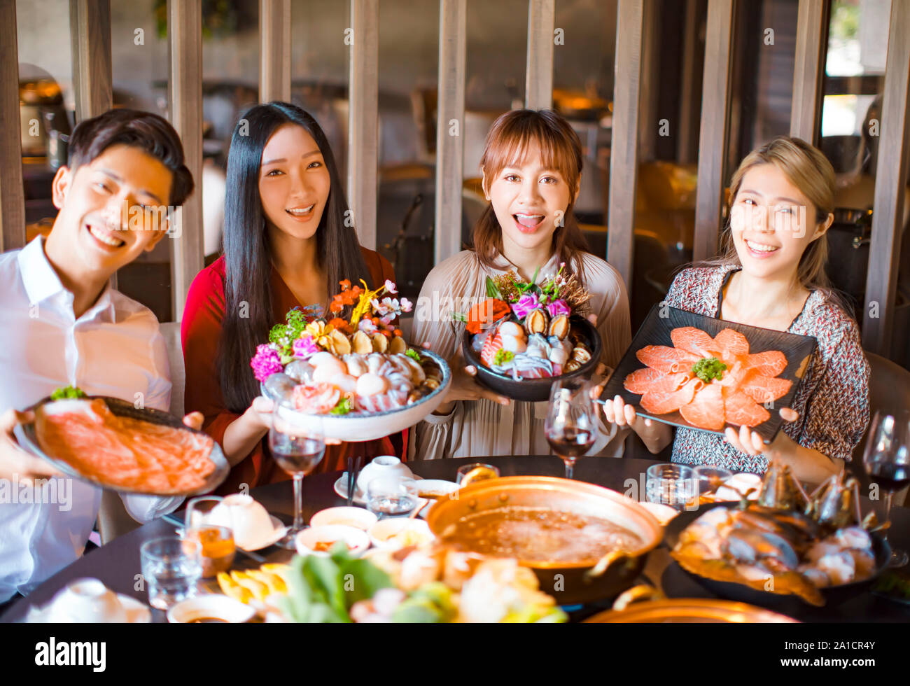 young friends showing seafood  beef and pork slices  in hot pot restaurant Stock Photo