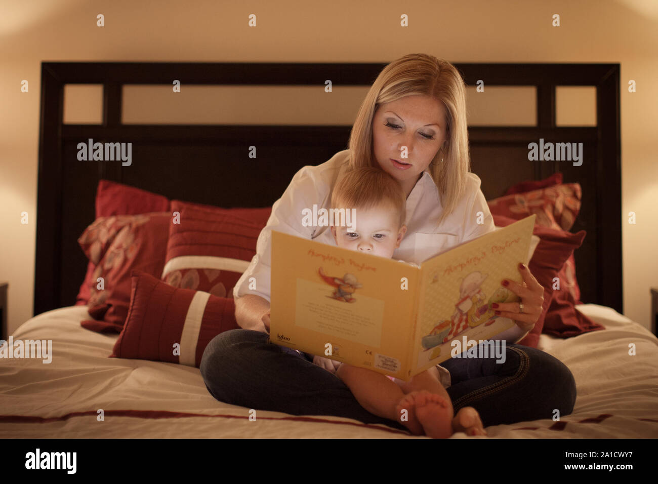 mother reading the book to her baby daughter in the bed Stock Photo