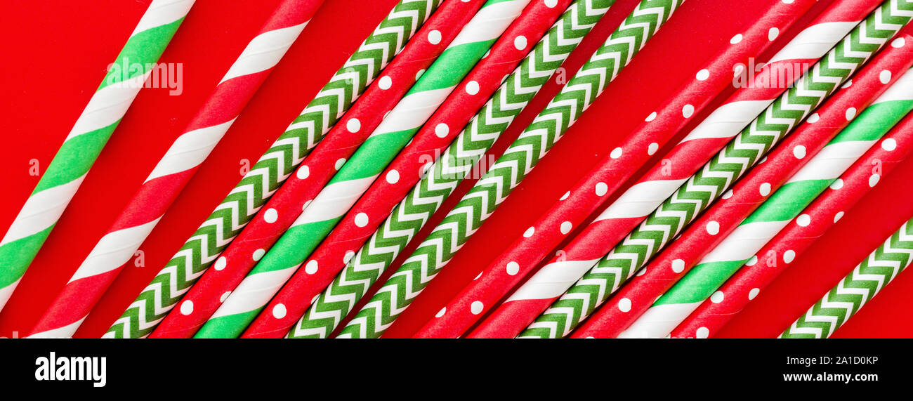 Striped drink straws on red background. Horizontal banner for web. New Year or Xmas pattern. Minimalism concept. Pop art style. Top view, Flat lay Stock Photo