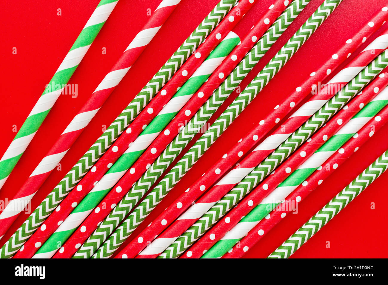 Striped drink straws of different colors on red background. New Year or Christmas pattern. Minimalism concept. Pop art style. Top view, Flat lay with Stock Photo