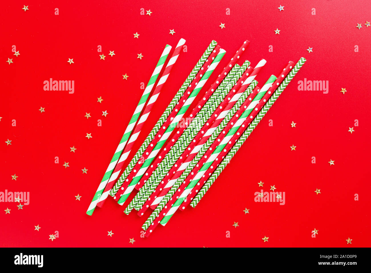 Striped drink straws of different colors on red background. New Year or Christmas pattern. Minimalism concept. Pop art style. Top view, Flat lay with Stock Photo