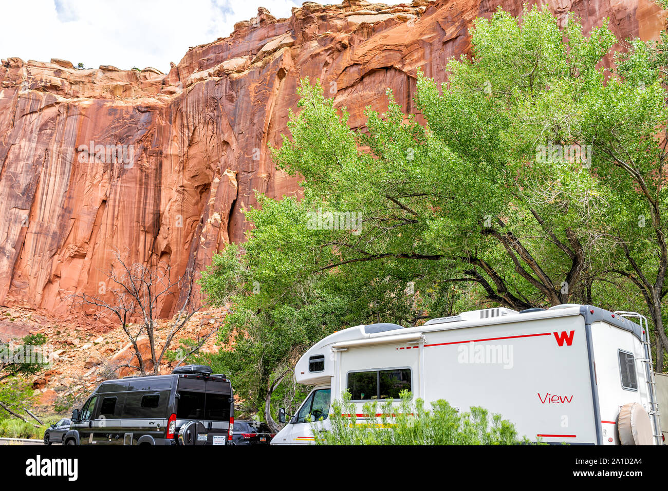 Fruita, USA - July 31, 2019: Car and RV in parking area near orchard in Capitol Reef National Monument in summer with red rock formation canyon Stock Photo