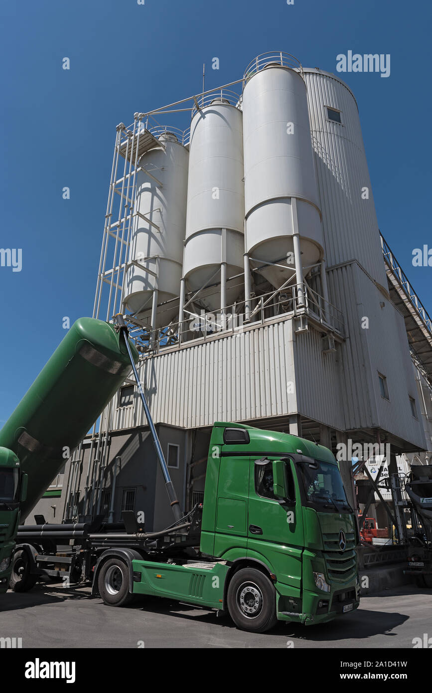 cement factory with silos and green truck mixing silo construction site industry manufacturing Stock Photo