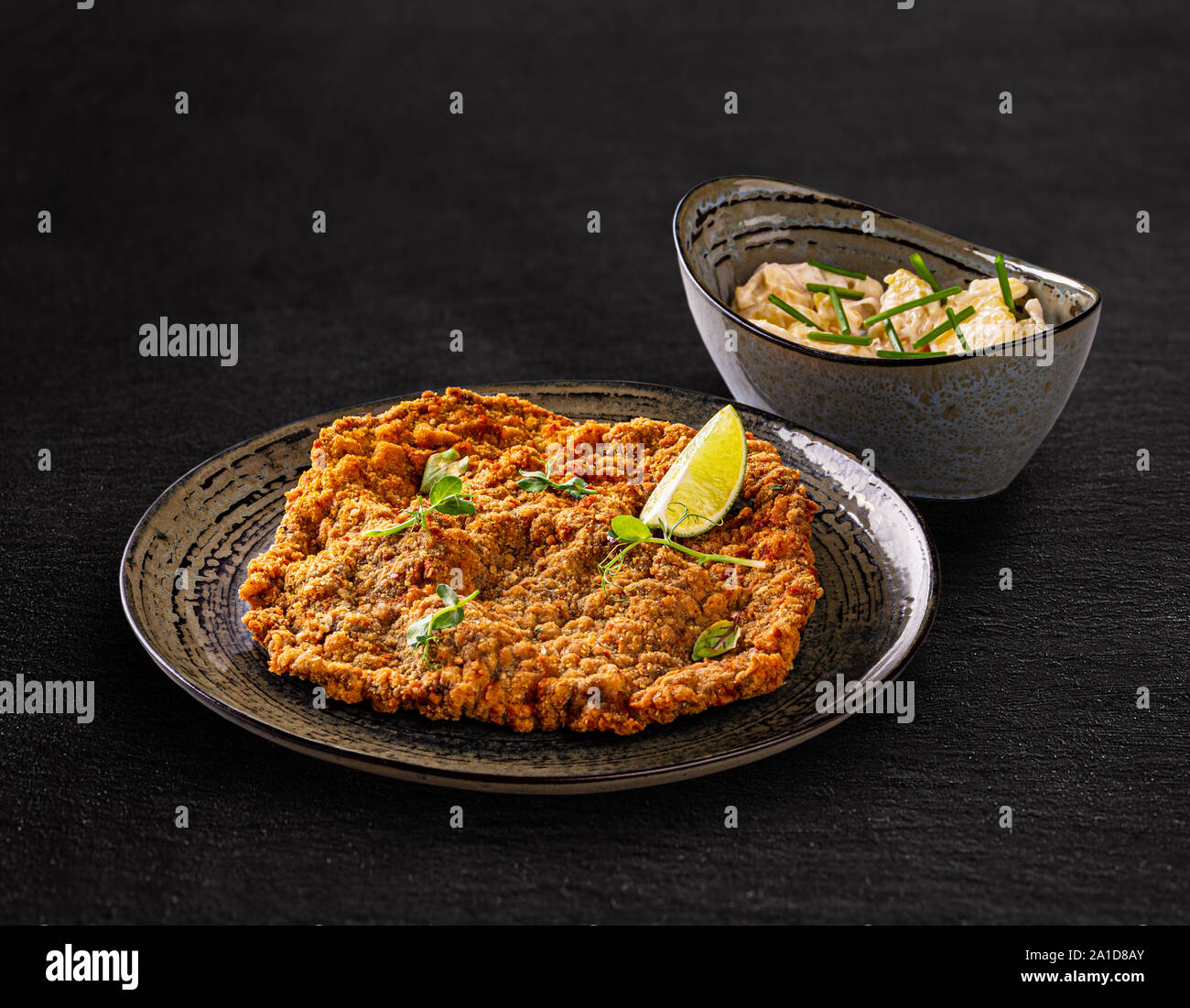Giant veal viennese schnitzel served with potato salad with chives Stock Photo