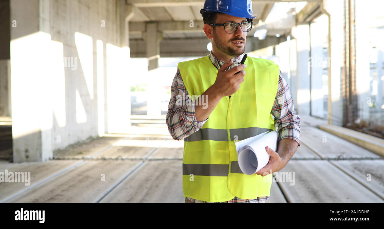 Male architect with blueprints using walkie-talkie Stock Photo