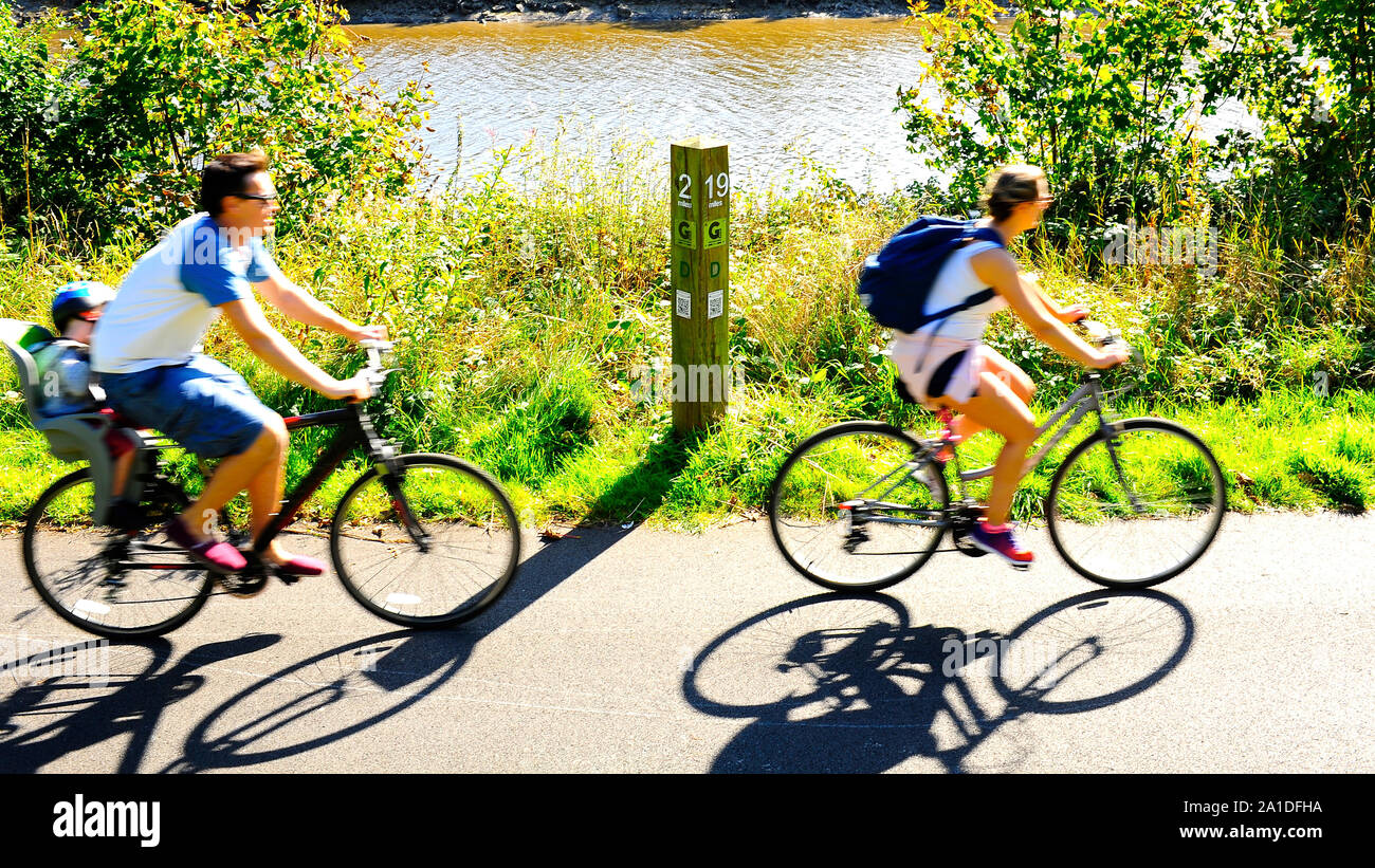 Young family cycle along the Preston Guild Wheel on the banks of the River Ribble on a summer day Stock Photo
