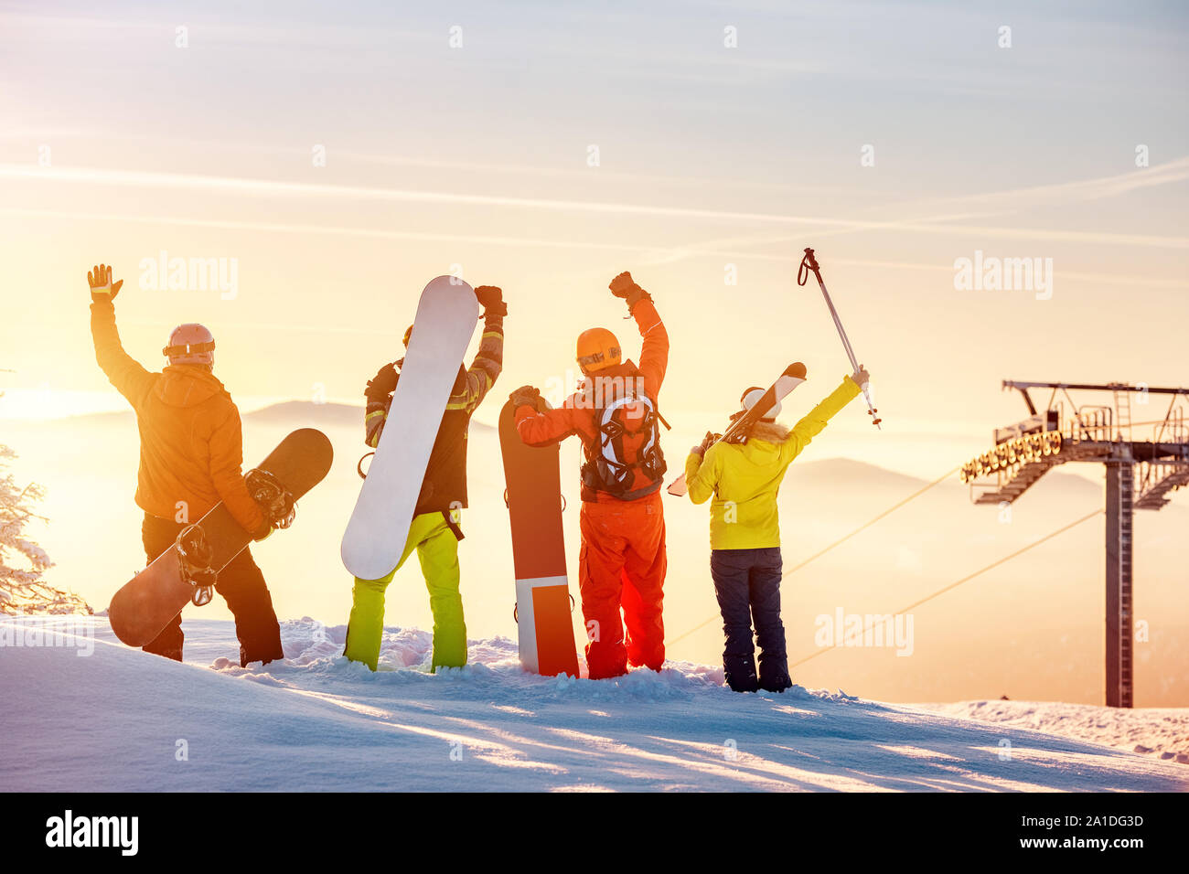 Group of happy friends skiers and snowboarders stands at sunset mountain top and having fun Stock Photo