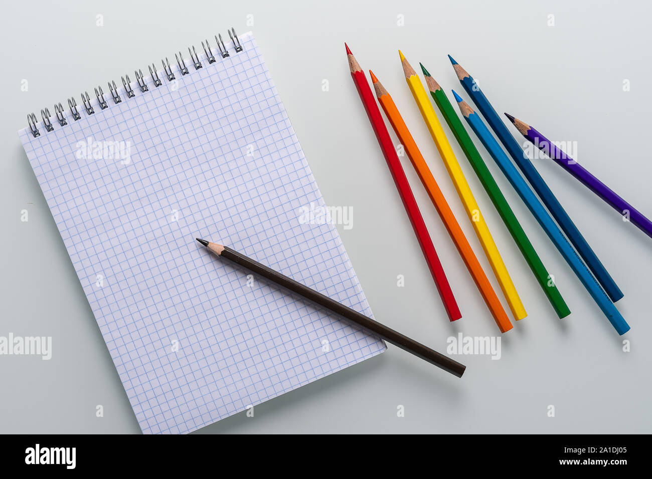 Clean notepad in a cage with a pencil lying on it and rainbow color ...