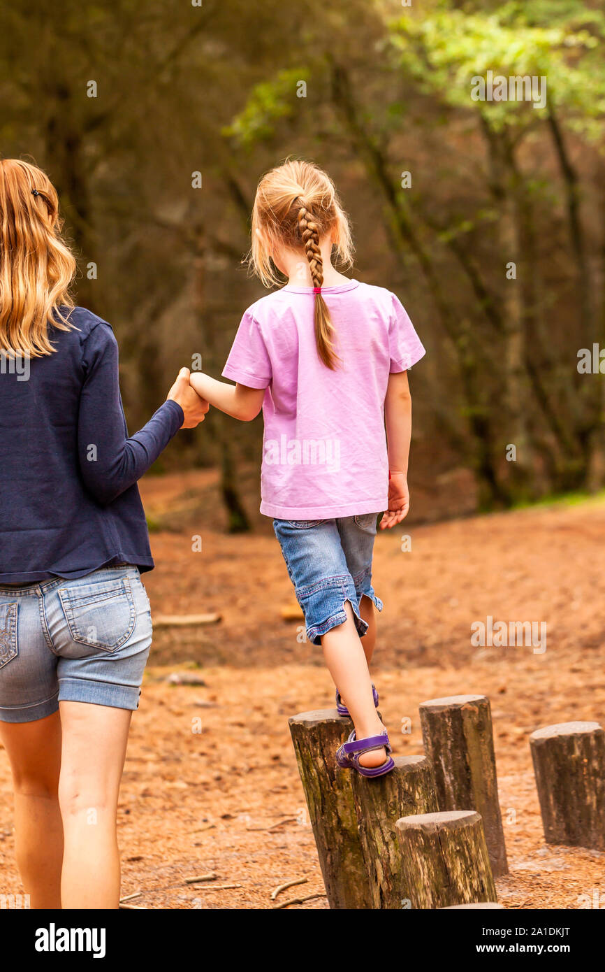 Mother Supporting daughter in the playground with climbing and hanging on a ladder. Stock Photo