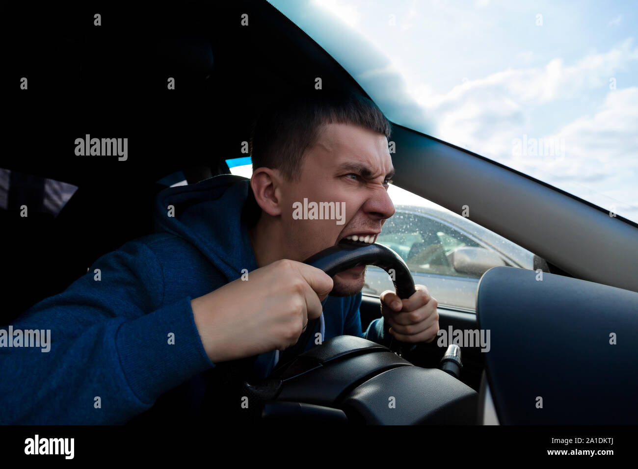 An emotional guy bites the steering wheel of a car while driving in a