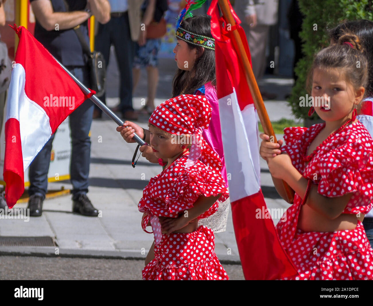 Peruvian girls in traditional costumes carry flags of their country during the XV Intercultural Week Parade in Valladolid Stock Photo