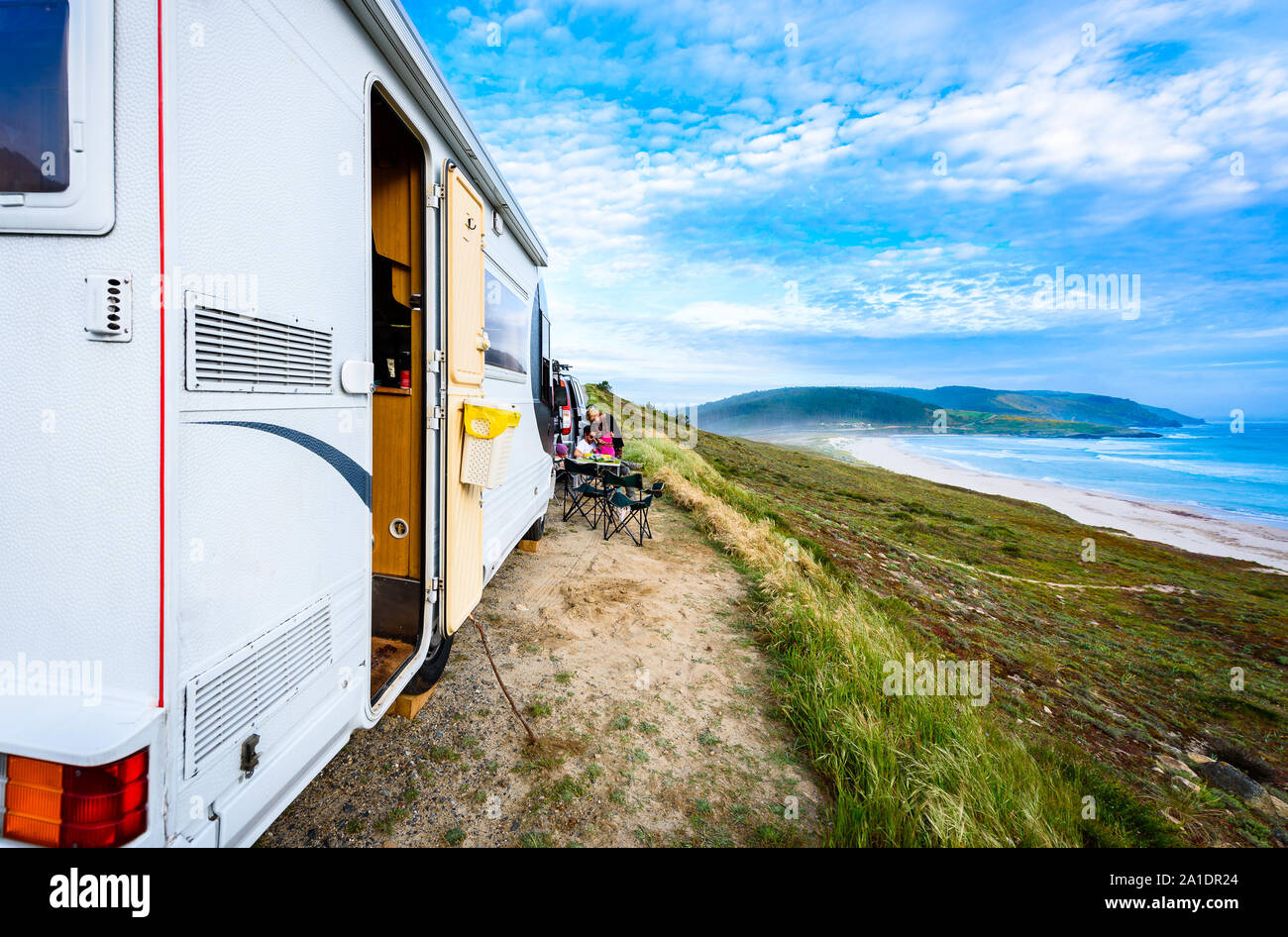 Motorhome RV and campervan are parked on a beach. Family on vacation is