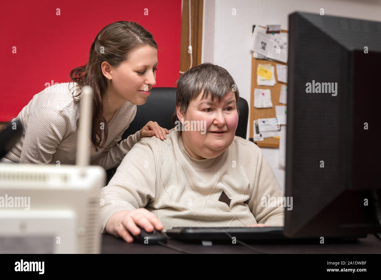 caregiver and mentally disabled woman learning at the computer, special education Stock Photo