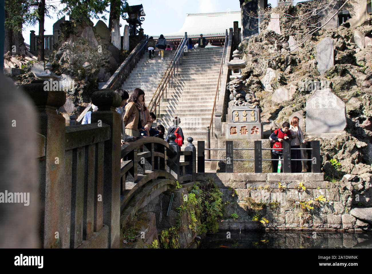 Japanese people and foreign traveler throwing coin to rock in pond rite ritual traditional in Naritasan Shinshoji Temple at Chiba Prefecture on March Stock Photo