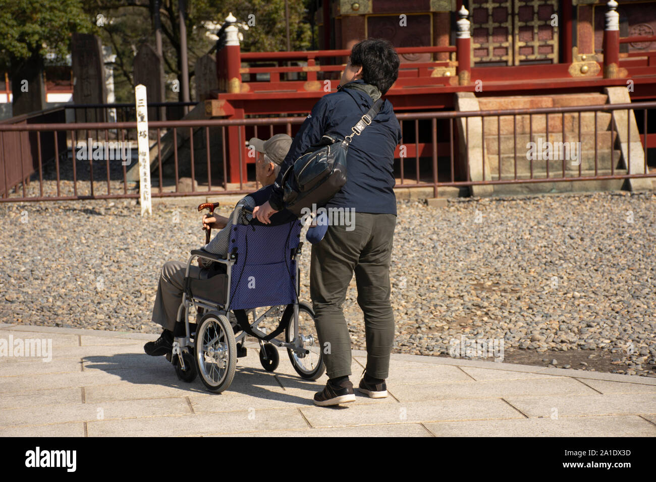 Japanese family people push wheelchair and bring oldman father walking visit and praying in