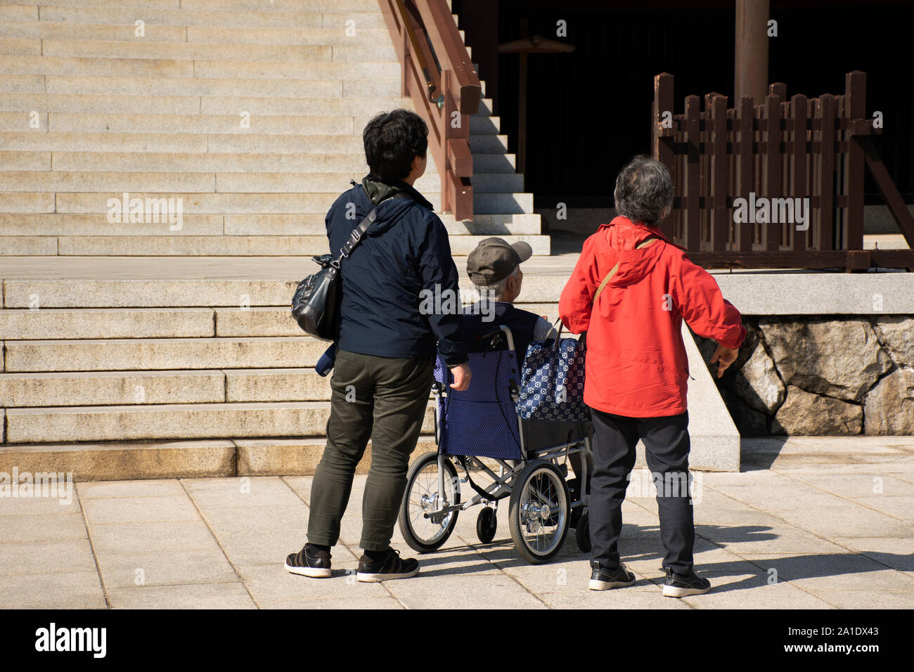 Japanese family people push wheelchair and bring oldman father walking visit and praying in