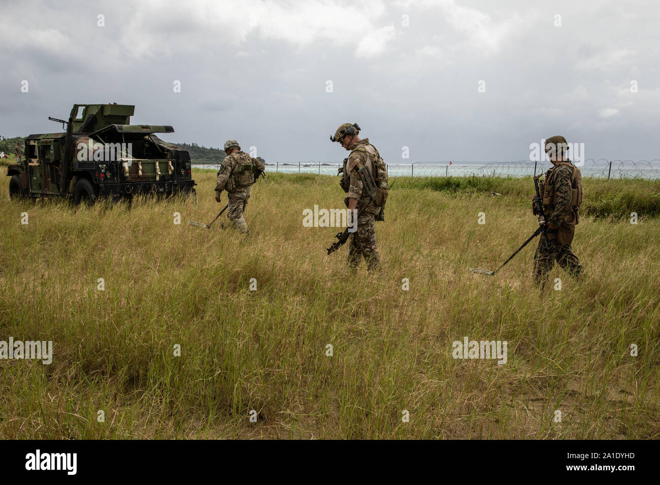U.S. Marine Corps Sgt. Jonathan Whitby (right), U.S. Air Force Senior Airman Benjamen Dring and U.S. Army Staff Sgt. James Ahn sweep for land mines during an explosive ordnance disposal exercise at Kin Blue Training Area, Okinawa, Japan, Sept. 19, 2019.  The EOD exercise was designed to simulate conventional warfare and the use of conventional ordnance and involved the participation of three U.S. military branches and over 43 different military occupational specialties within III Marine Expeditionary Force. Whitby, a native of Tempe, Arizona, is an EOD technician with EOD Company, 9th Engineer Stock Photo