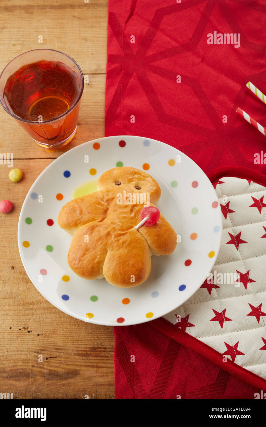 Freshly baked Stuten bread man on a festive red themed table with glass of beverage viewed top down for a traditional St Nicholas celebration Stock Photo