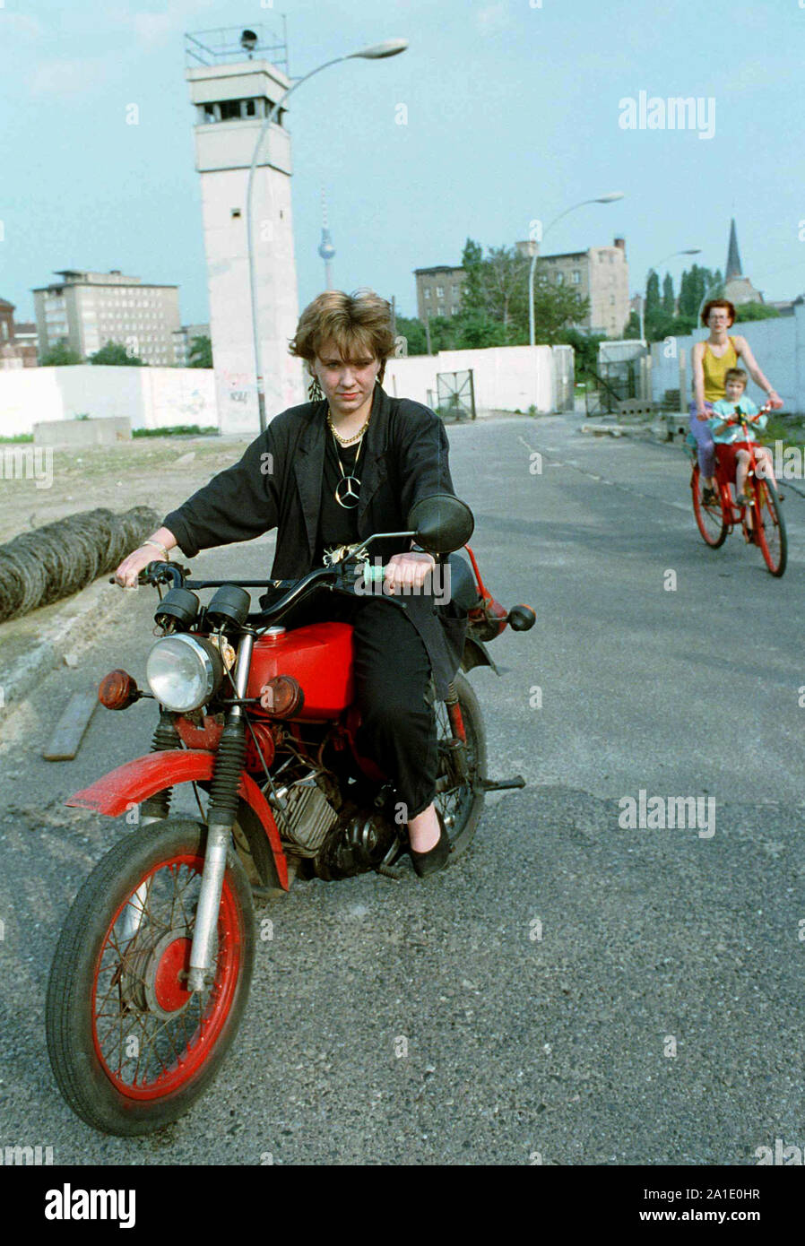 04 April 1990, Berlin, Mitte: A young woman drives on 4.4.1990 with her  Simson S50 moped in the former wall strip at the north station and  practices for the moped test. In