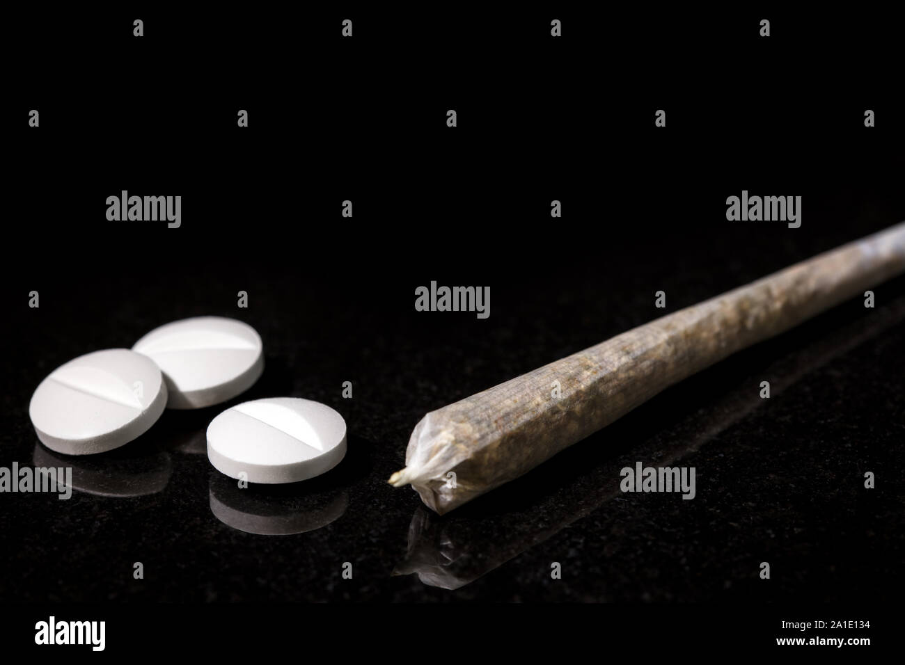 Cannabis Joint with white Pills, concept medicine and pharmacy, black background Stock Photo