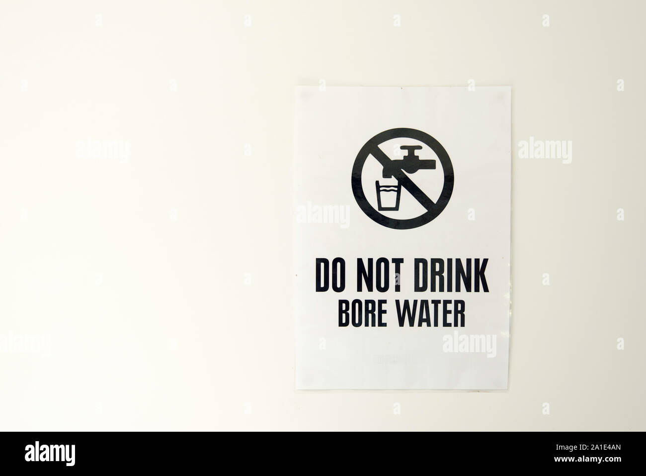 A bore water sign pinned to a white wall warning people not to drink
