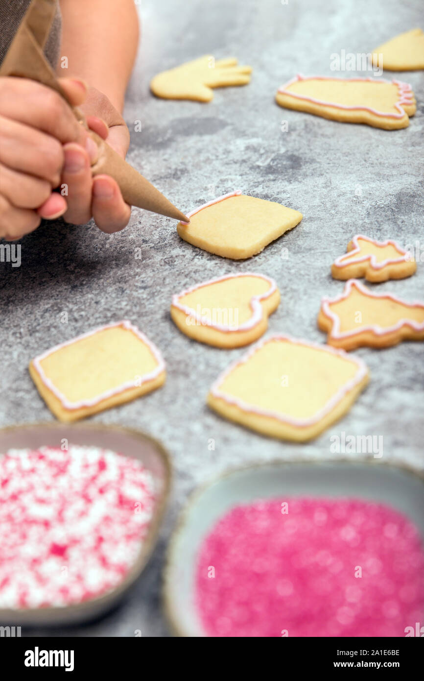 Confectionist is decoration christmas cookies with icing, frosting and sugar pearls with forcing bag Stock Photo