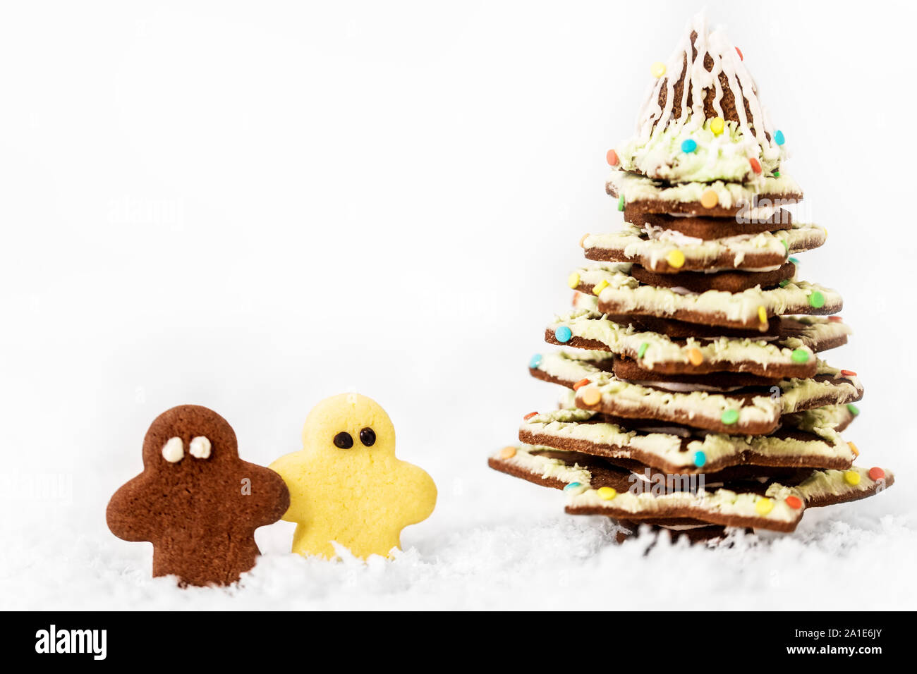 Christmas tree and little man cookies standing in the snow, white background with copyspace Stock Photo