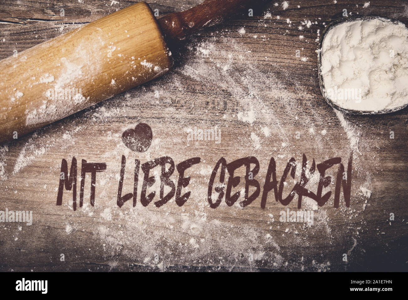 Dough roll and flour on wooden table, german text mit liebe gebacken which means baked with love Stock Photo