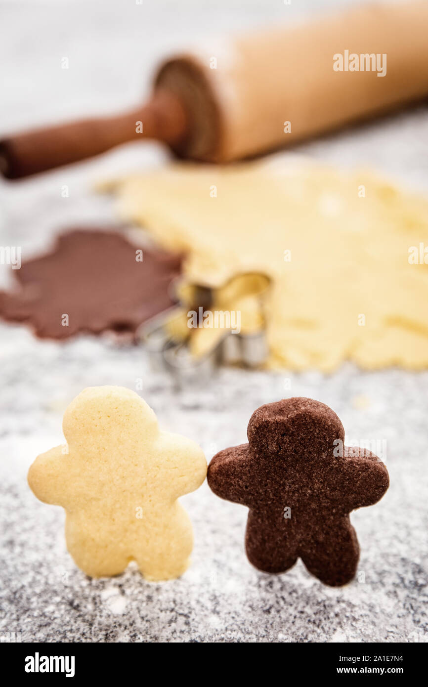 Black and white couple cookies with dough in the background, concept intercultural friendship or love Stock Photo