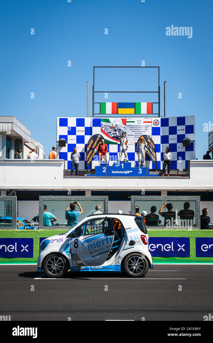 Vallelunga, Italy september 14 2019. Smart fortwo electric engine racing car on asphalt track in circuit grid with podium and people in background Stock Photo