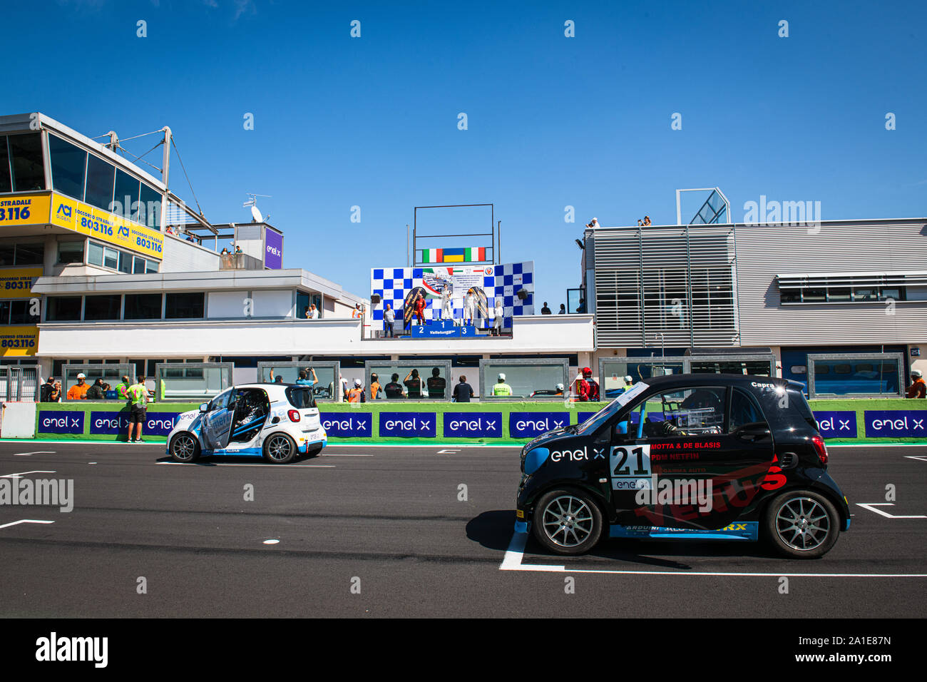 Vallelunga, Italy september 14 2019. Smart fortwo electric engine racing car on asphalt track in circuit grid with podium and people in background Stock Photo