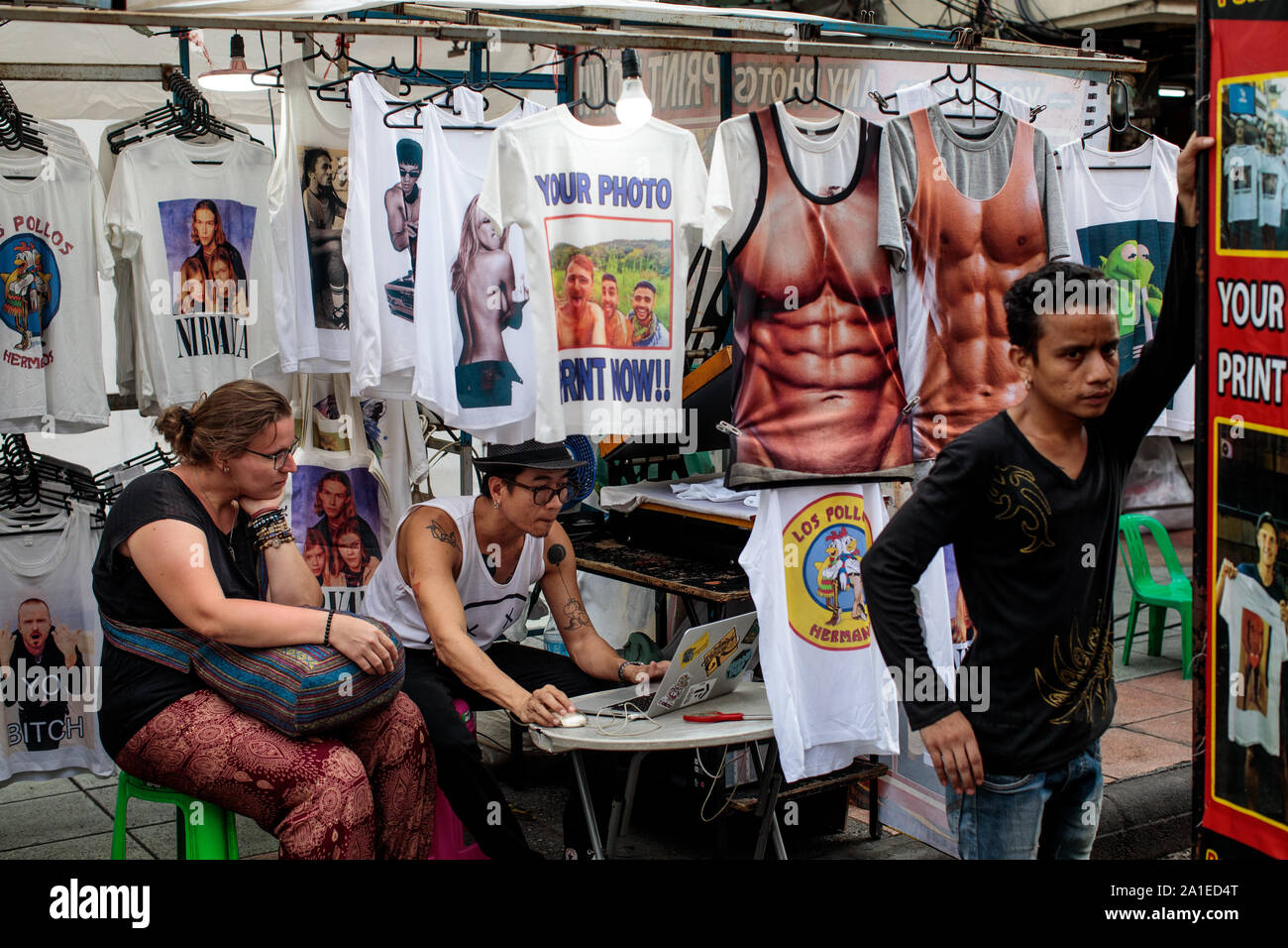 BANGKOK, THAILAND: A street vendor designs a personalised t shirt for a  tourist on Khao San Road in Bangkok, Thailand on August 27th, 2019.  Bangkoks bustling Khao San Road - a strip