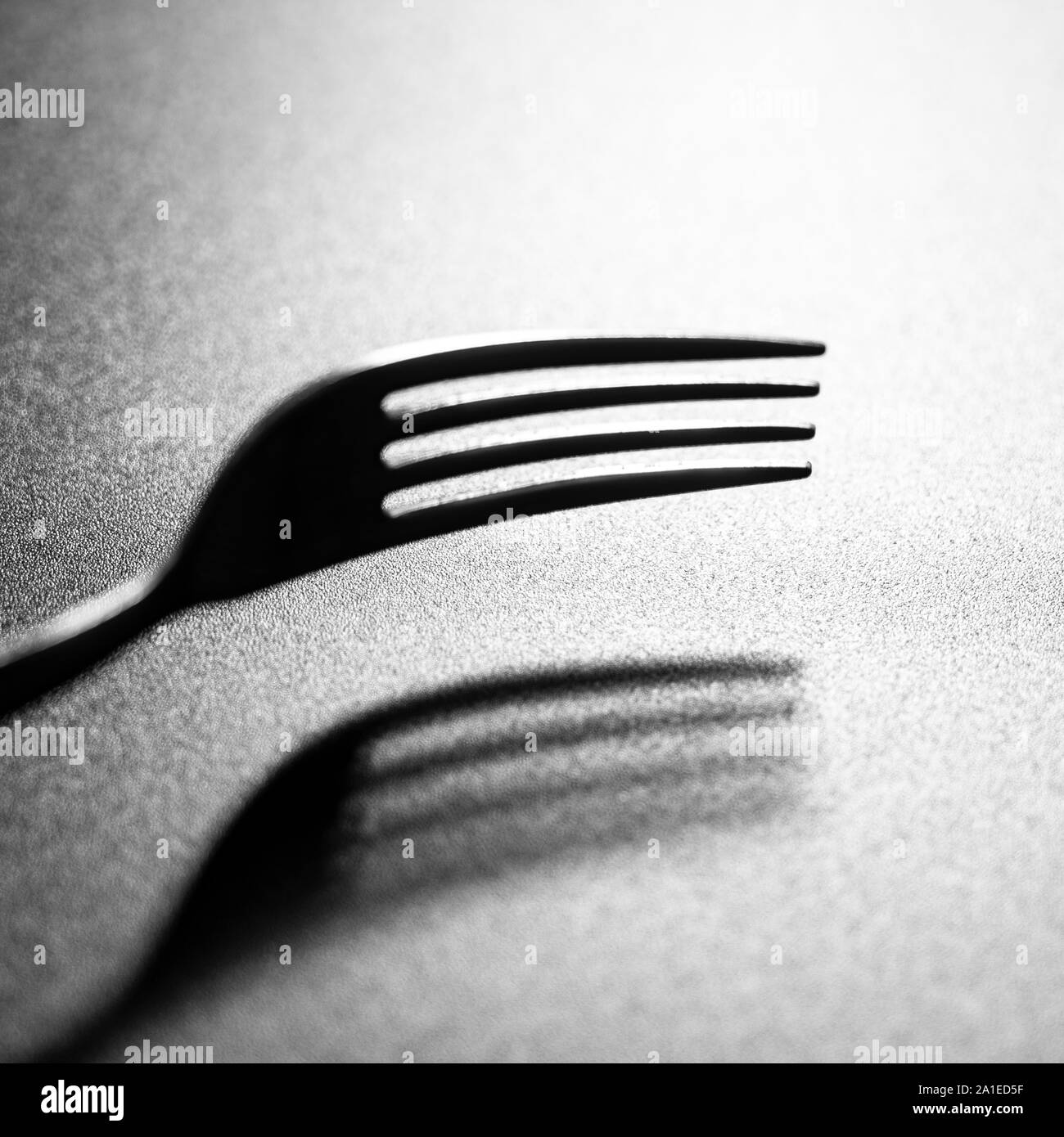 the shadow of a fork on a black surface Stock Photo