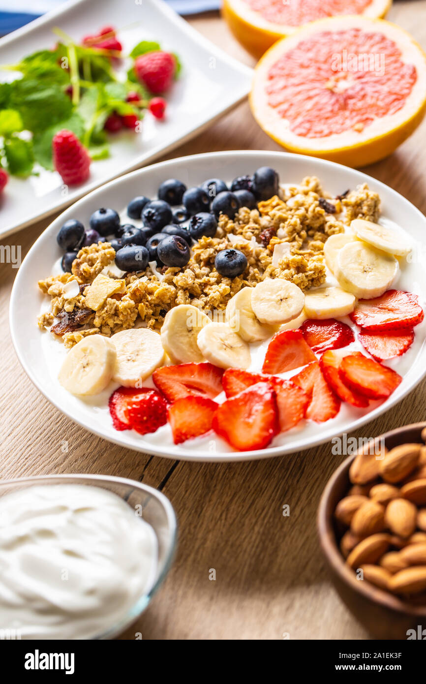 Healthy breakfast served with plate of yogurt muesli blueberries strawberries and banana. Stock Photo