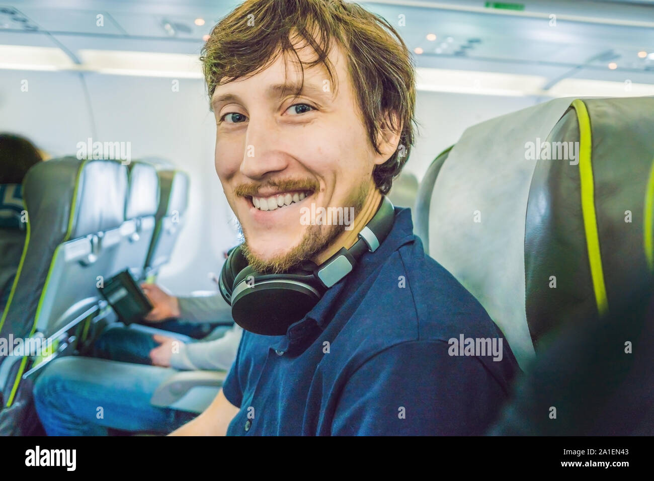 Passenger in airplane using headphones. man in plane cabin using smart