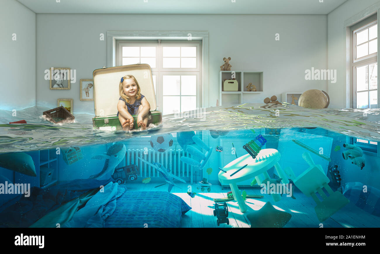 3 year old blond girl sitting inside a vintage suitcase floats on water in her flooded bedroom. Concept of difficulty and carefree. Stock Photo
