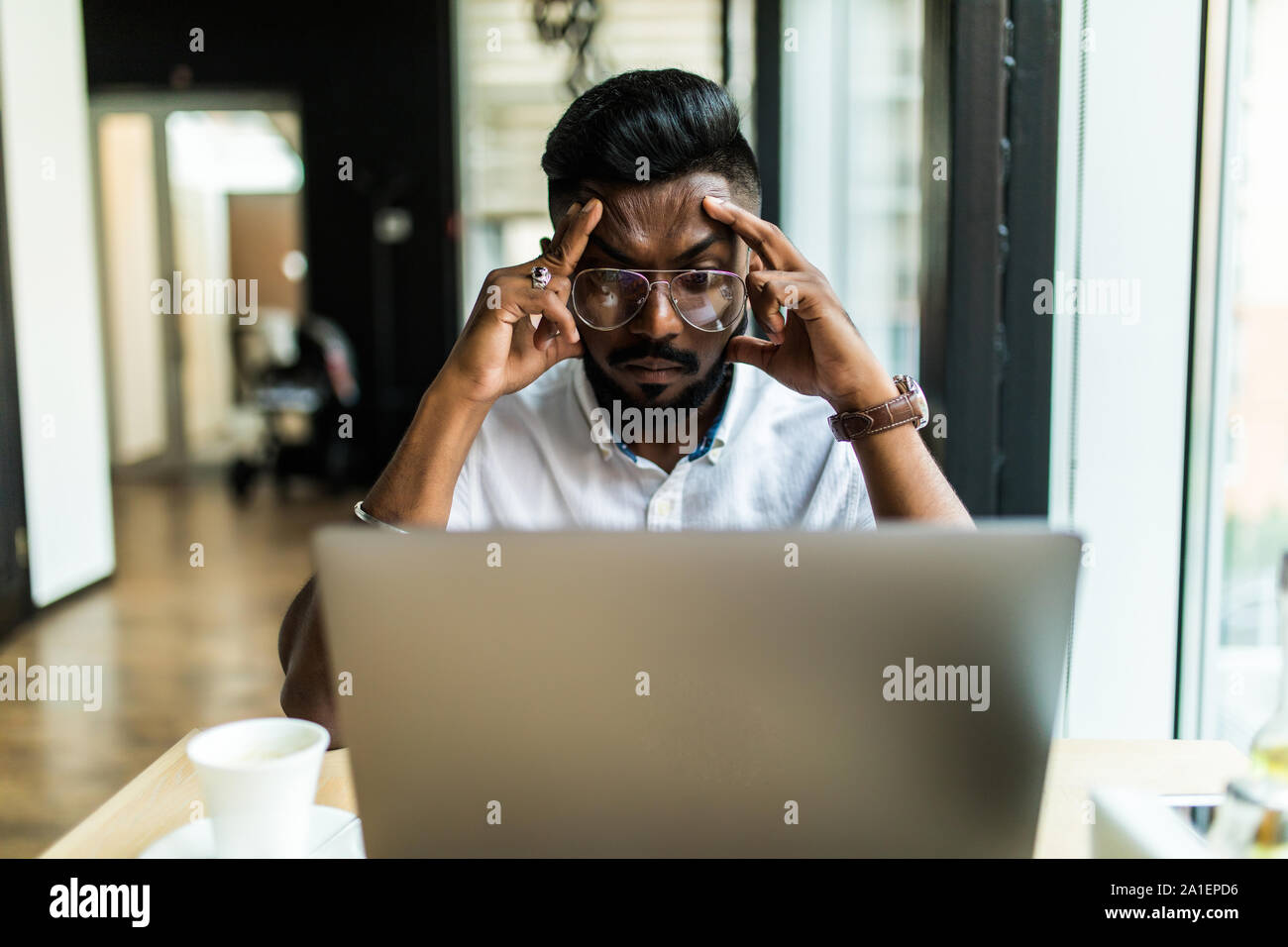 Young Asian businessman suffering from tired eyes after long hours of using laptop. Stock Photo