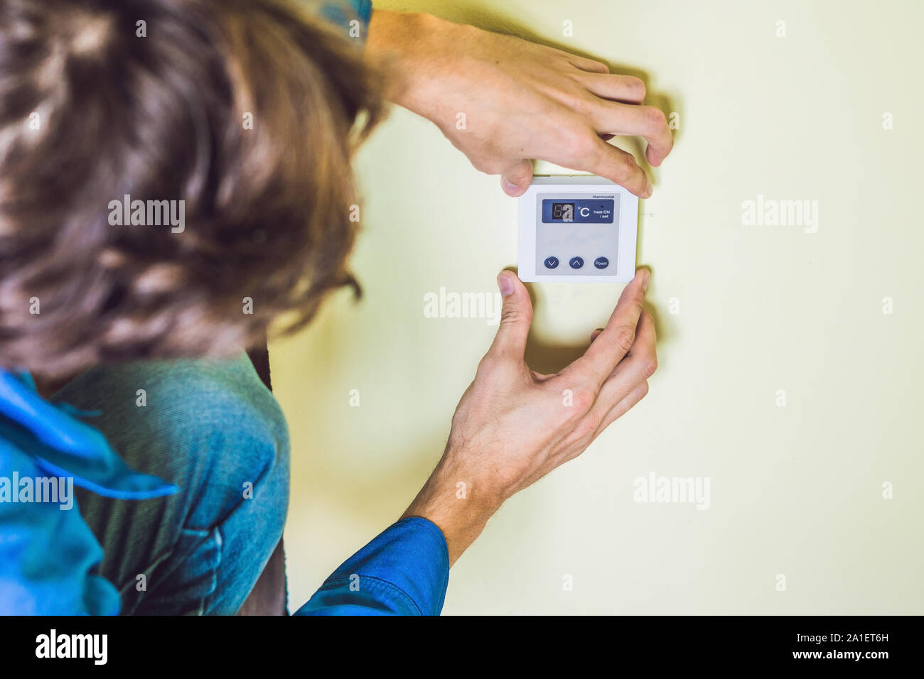electrician installing an electrical thermostat in a new house Stock